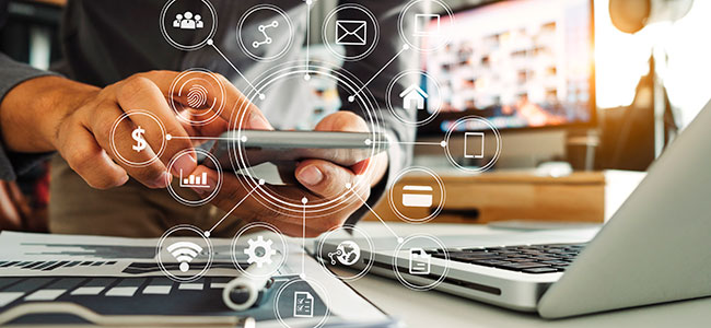 Matkapuhelin, läppäri ja lehti.